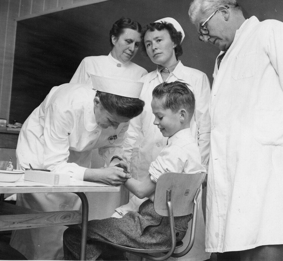 Nes på Romerike, 1956: Den første vaksineringen mot poliomyelitt startet ved Framtun skole. Helsesøster Ruth Hauge vaksinerer den første eleven Ola Eide. Distriktslege Øverland og sykepleierskene Borghild Henden og Signe Berg følger med. Foto: Aage Storløkken, Aktuell/Scanpix
